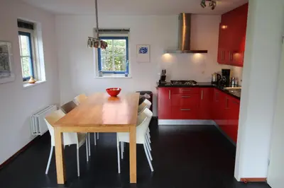 a kitchen with a wooden table and red cabinets at Vakantiehuis Zeeduinenbos in Schoorl