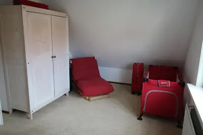 a room with a red chair and a cabinet at Vakantiehuis Zeeduinenbos in Schoorl