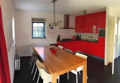 a kitchen with a wooden table and red cabinets at Vakantiehuis Zeeduinenbos in Schoorl
