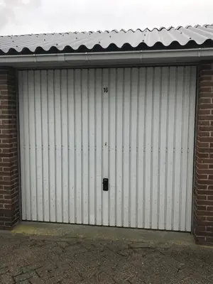 a white garage door with a number on it at Huisje 16 in Noordwijk aan Zee