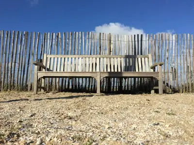 a wooden bench sitting in front of a fence at Huisje 16 in Noordwijk aan Zee