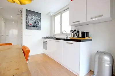 a kitchen with white cabinets and a wooden table at 2 bedroom loft near Rijksmuseum in Amsterdam