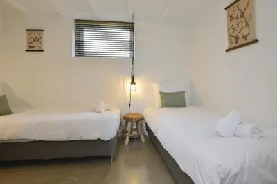 two twin beds in a room with a stool between them at Endless Summer Beach Apartments in Zandvoort