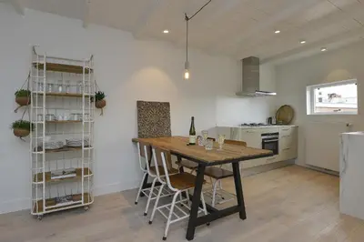 a kitchen with a wooden table and chairs in a room at Endless Summer Beach Apartments in Zandvoort