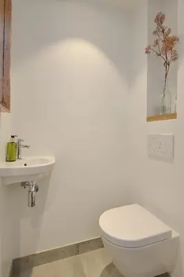 a white bathroom with a toilet and a sink at Endless Summer Beach Apartments in Zandvoort