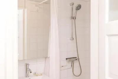 a shower with a white shower curtain in a bathroom at Dare to be different in Zandvoort