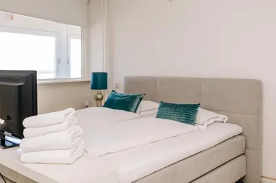 a bed with white sheets and green pillows at Dare to be different in Zandvoort
