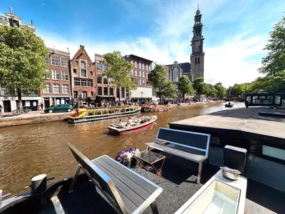 a river with boats in a city with a clock tower at Prince Royal B&B in Amsterdam