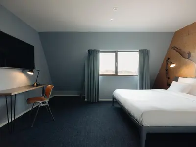 a hotel room with a bed and a desk and a window at Conscious Hotel The Tire Station in Amsterdam