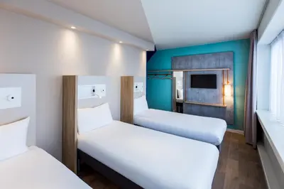 two beds in a room with a tv at ibis budget Amsterdam City South in Amstelveen