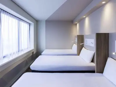 two beds in a small room with a window at ibis budget Amsterdam City South in Amstelveen