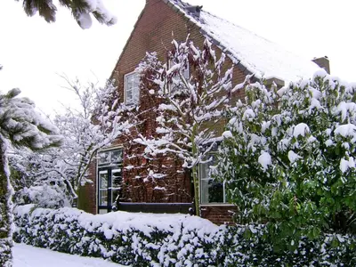 a house covered in snow in the yard at Hövell in Huizen