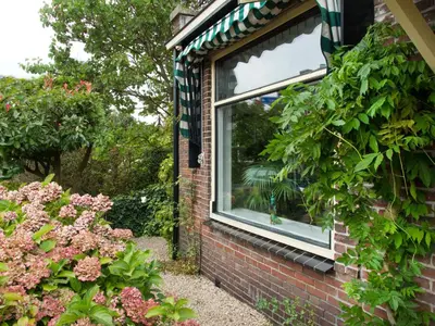 a window on the side of a brick house with flowers at Hövell in Huizen
