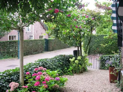 a garden with pink flowers and trees and a building at Hövell in Huizen