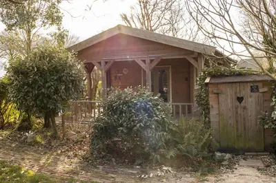 a small house with a porch and a fence at Chalet Ben in Broek in Benningbroek