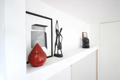 a white shelf with a red vase and pictures at Beautiful 2 floor Vondelpark apartment. in Amsterdam