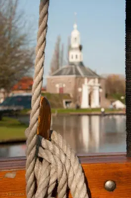 a rope hanging from a window with a view of a church at Zeilschip De Vrouw Dina in Leiden