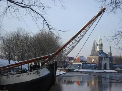 a boat in the water in front of a church at Zeilschip De Vrouw Dina in Leiden