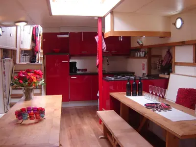 a kitchen with red cabinets and a wooden table at Zeilschip De Vrouw Dina in Leiden