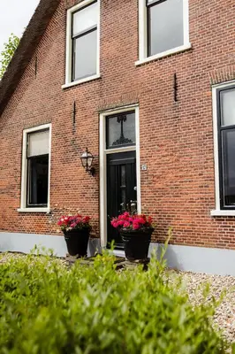 a brick building with two potted plants in front of a door at Boutique vakantiehuis Het Stalhuys in Reeuwijk