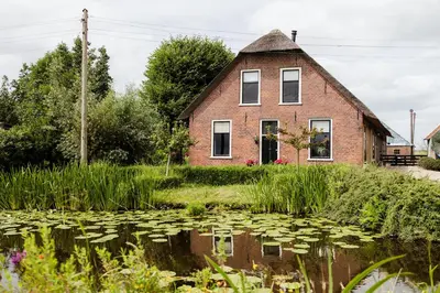 a house with a pond in front of it at Boutique vakantiehuis Het Stalhuys in Reeuwijk