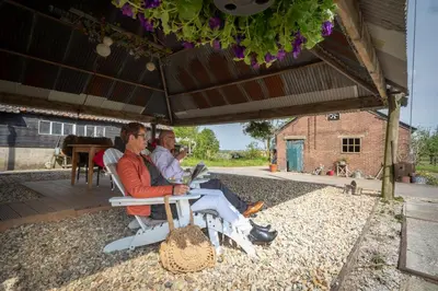 a group of people sitting in chairs under an umbrella at Boutique vakantiehuis Het Stalhuys in Reeuwijk