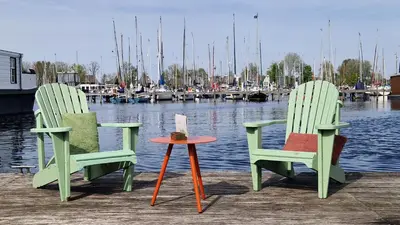 two chairs and a table on a dock with boats at Marinaparcs Naarden in Naarden
