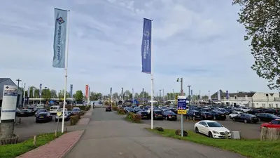a parking lot with parked cars and blue flags at Marinaparcs Naarden in Naarden