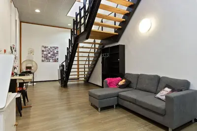 a living room with a couch and a staircase at Hostelle - women only hostel Amsterdam in Amsterdam