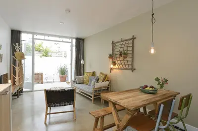 a kitchen and living room with a wooden table at Follow The Sun Apartment in Zandvoort