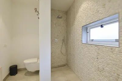 a bathroom with a toilet and a window at Follow The Sun Apartment in Zandvoort