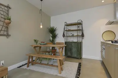 a kitchen with a table and a bench in a room at Follow The Sun Apartment in Zandvoort