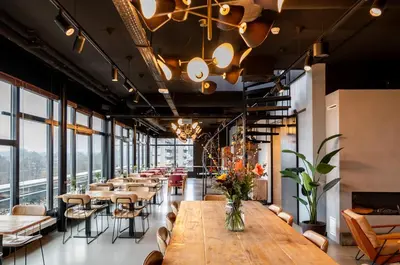a dining room with tables and chairs and windows at Cityden Zuidas in Amstelveen