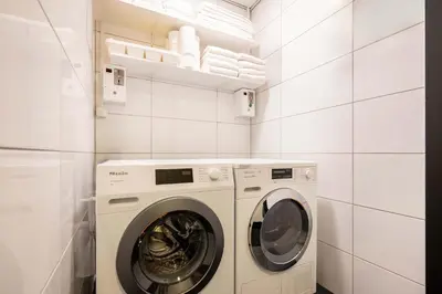 a white laundry room with a washer and dryer at Cityden Zuidas in Amstelveen