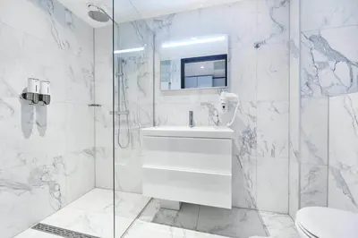a white bathroom with a sink and a shower at Cityden Zuidas in Amstelveen