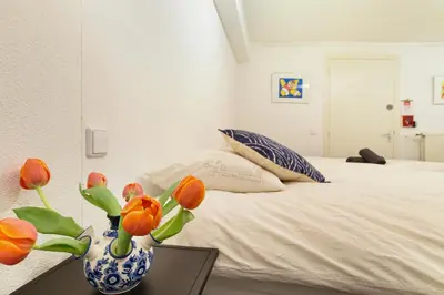 a bedroom with a bed with a vase with flowers in it at Only Friends in Amsterdam