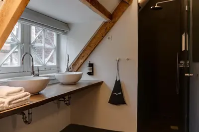 a bathroom with two sinks and a window at Vesting Hotel Naarden in Naarden