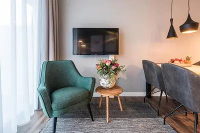 a living room with two chairs and a table with a vase of flowers at YAYS Amsterdam North by Numa in Amsterdam