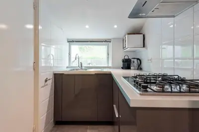 a white kitchen with a stove and a sink at Anne's Family Home with private parking in Zandvoort