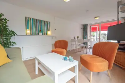 a living room with a couch and chairs and a tv at Anne's Family Home with private parking in Zandvoort