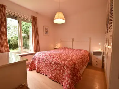 a bedroom with a bed and two windows at Holiday Home in Bergen aan Zee with Terrace in Bergen aan Zee