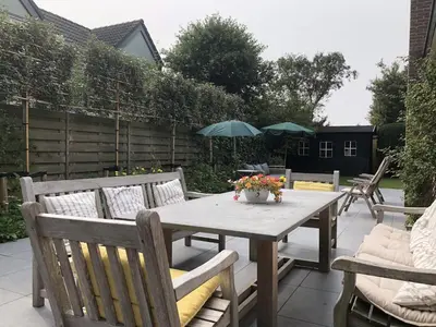 a wooden table and chairs on a patio at Holiday Home in Bergen aan Zee with Terrace in Bergen aan Zee