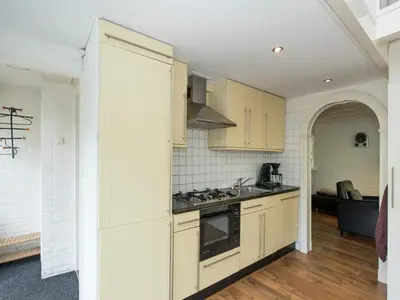 a kitchen with white cabinets and a stove top oven at Holiday Home in Noordwijkerhout by Forest & Lake in Noordwijkerhout