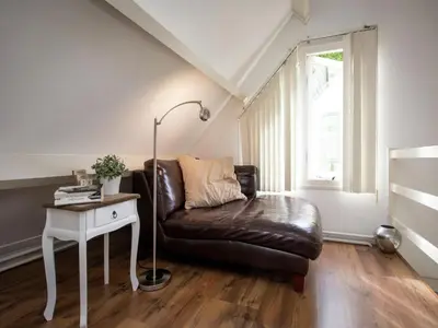 a living room with a leather couch and a table at Holiday Home in Noordwijkerhout by Forest & Lake in Noordwijkerhout