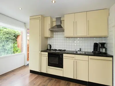 a kitchen with yellow cabinets and a stove top oven at Holiday Home in Noordwijkerhout by Forest & Lake in Noordwijkerhout