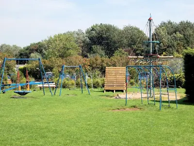 a playground with two swings in a grass field at Holiday Home in Noordwijkerhout by Forest & Lake in Noordwijkerhout