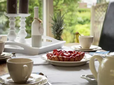 a table with a pie on a plate on a table with cups at Holiday Home in Noordwijkerhout by Forest & Lake in Noordwijkerhout