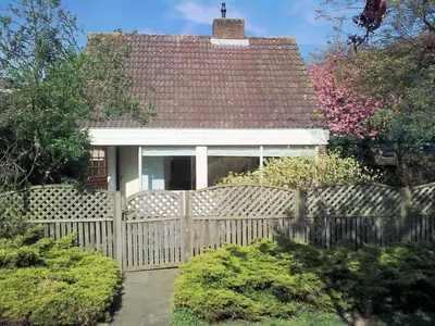 a white house with a fence in front of it at Holiday Home in Noordwijkerhout by Forest & Lake in Noordwijkerhout