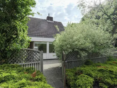 a white house with a fence and trees at Holiday Home in Noordwijkerhout by Forest & Lake in Noordwijkerhout