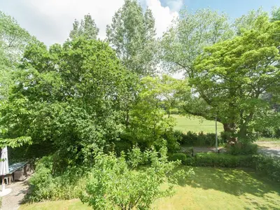 a view of a park with trees and a bench at Peaceful Dune Retreat with Garden in Schoorl